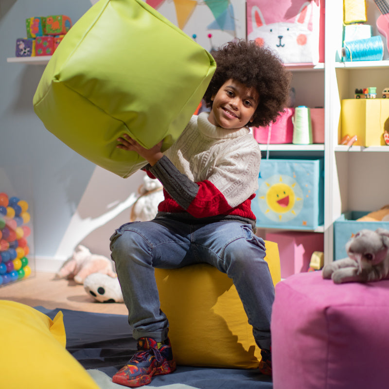 bambino che gioca con pouf colorato in similpelle